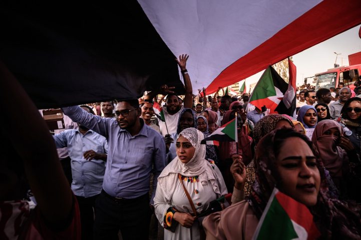 متظاهرون يسيرون تحت العلم السوداني/ نيويورك تايمز