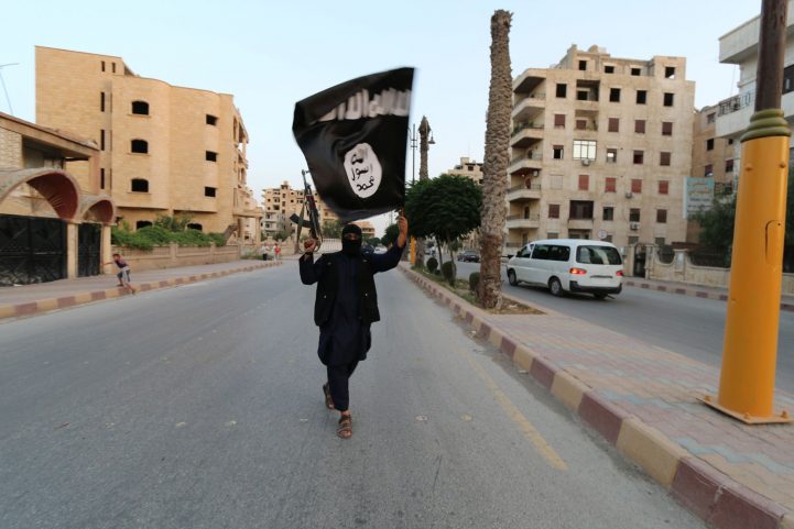 صورة إرشيفية لأحد مقاتلي داعش يلوح بعلم التنظيم في مدينة الرقة/ رويترز