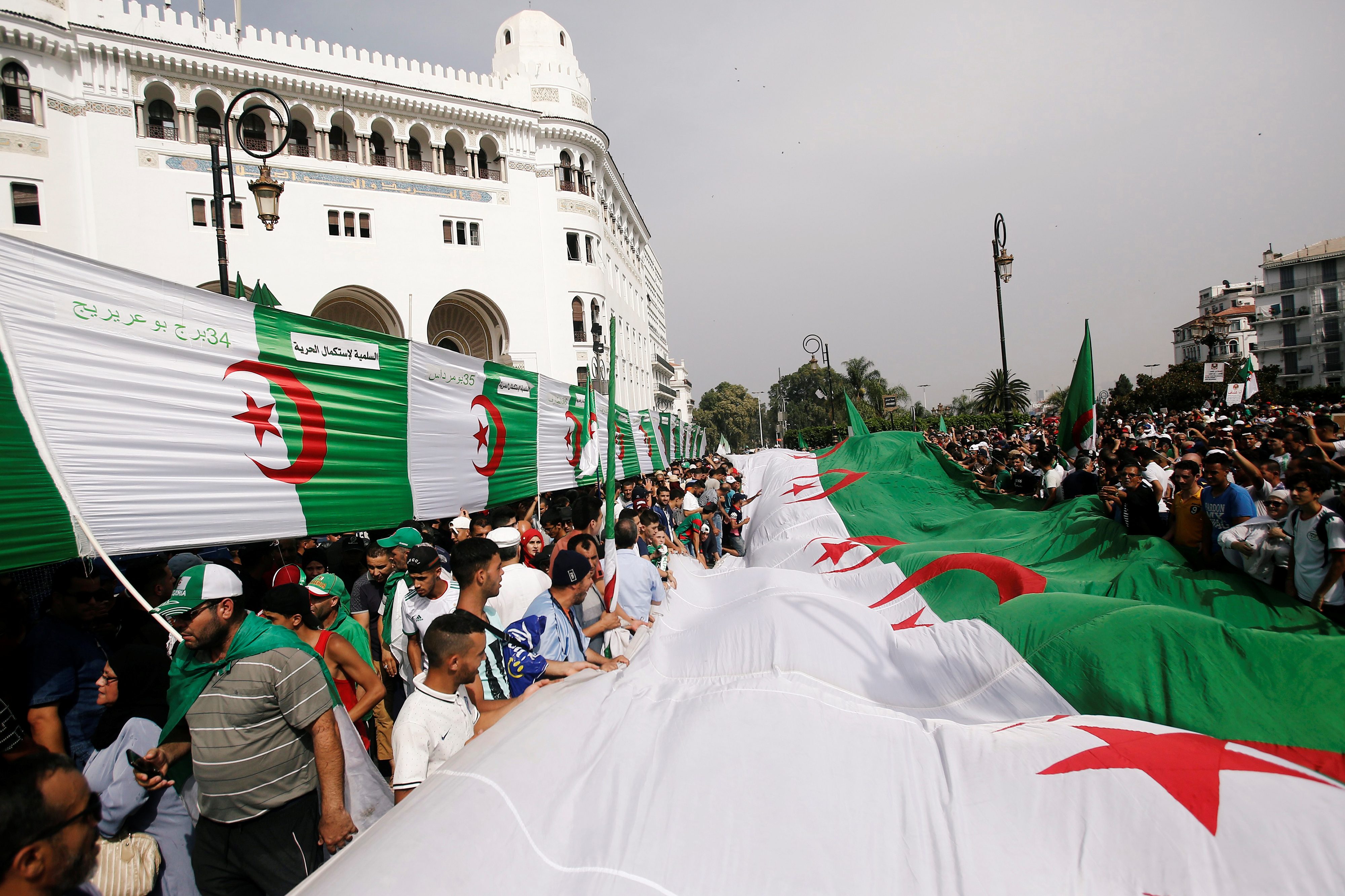 المتظاهرون يحملون الأعلام في أثناء احتجاجاتهم المطالبة بإزالة النخبة الحاكمة/ رويترز