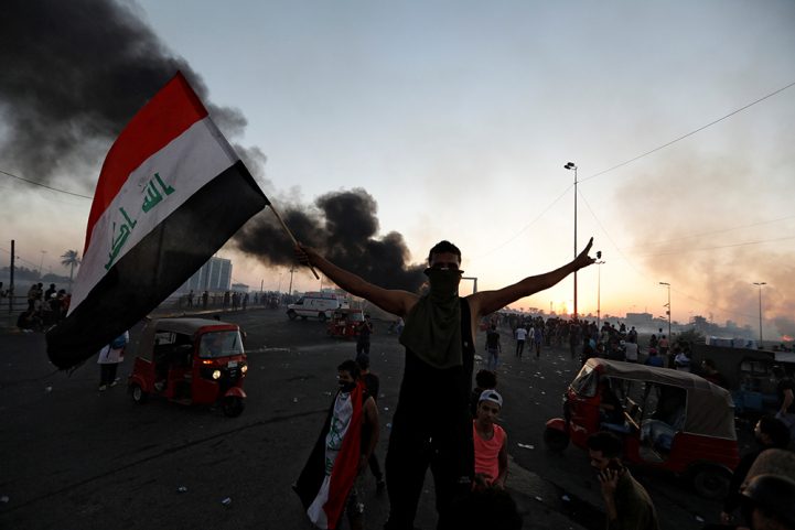 متظاهر عراقي يرفع علم بلاده خلال الاحتجاجات التي طالبت بإسقاط النظام، أكتوبر 2019/ رويترز