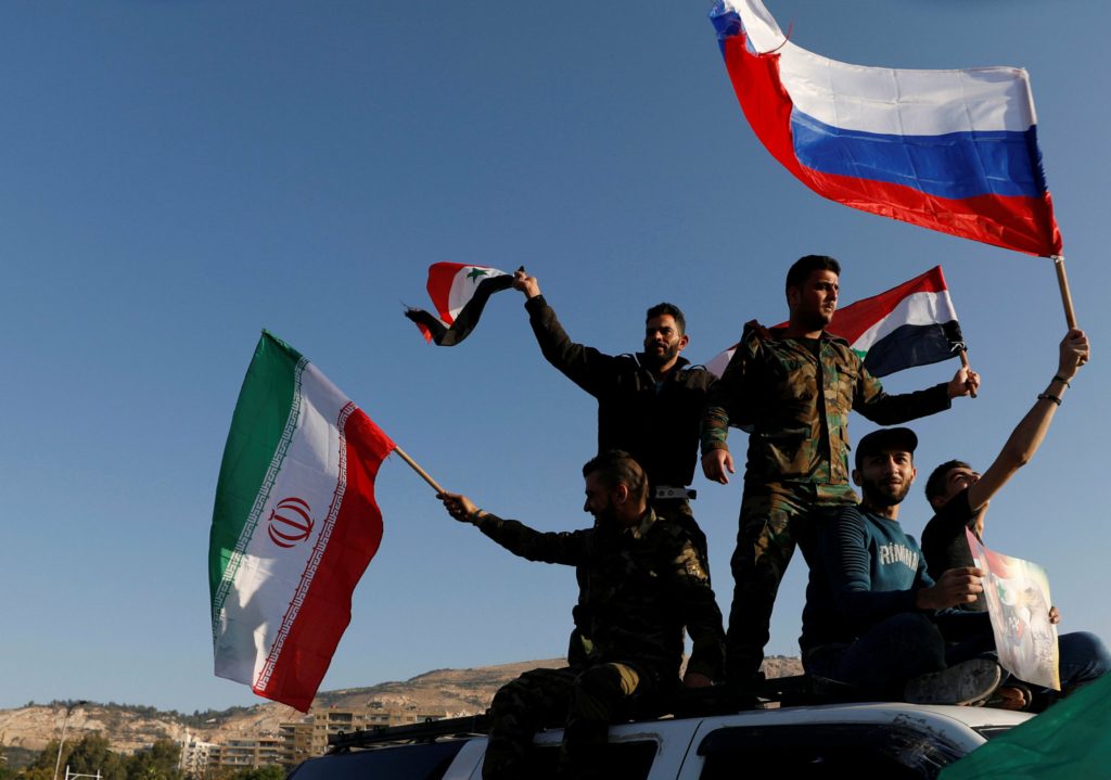 سوريون يرفعون أعلام سوريا وإيران وروسيا