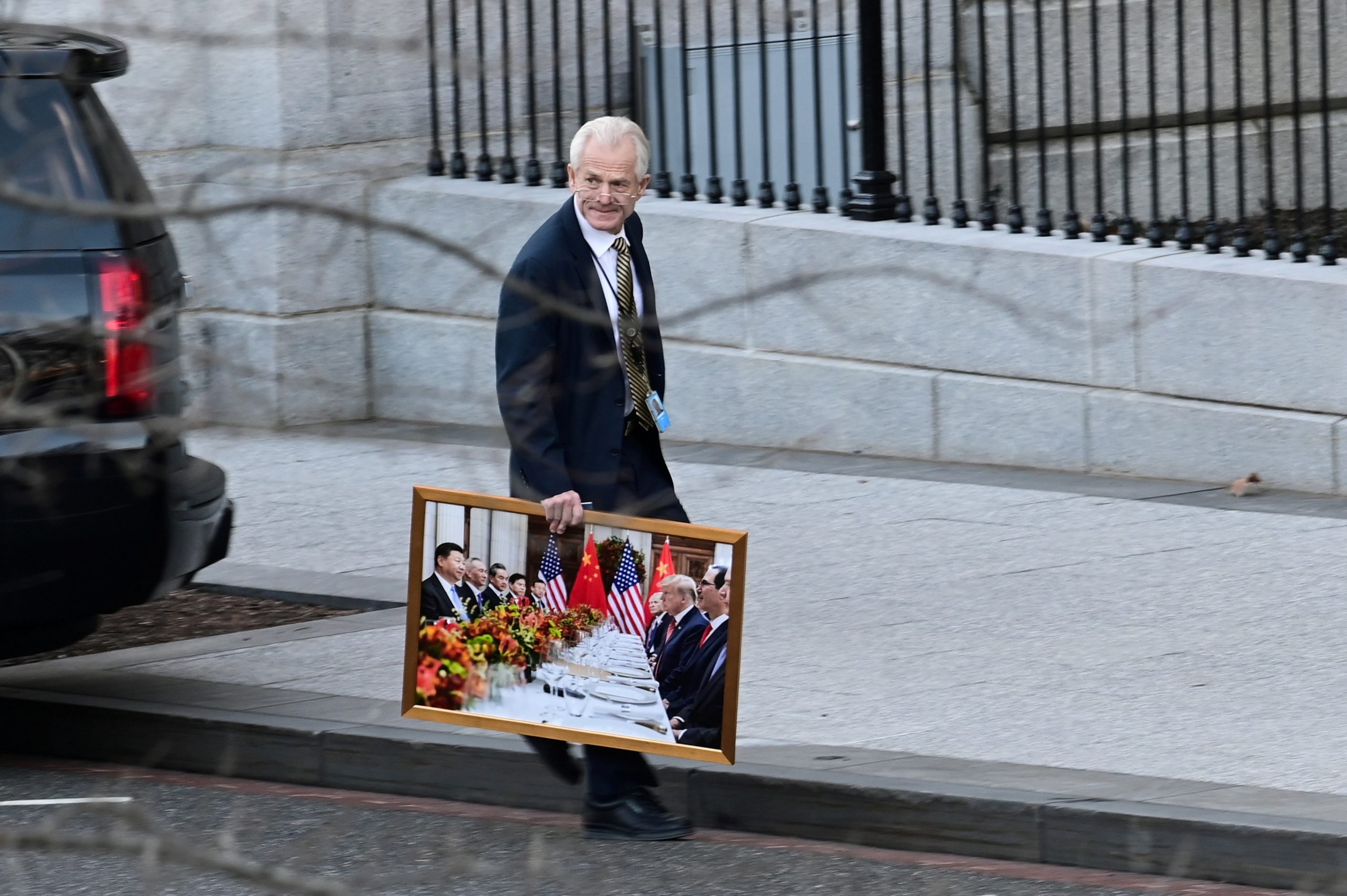 مستشار البيت الأبيض للتجارة، بيتر نافارو، يغادر الجناح الغربي للبيت الأبيض، ويحمل صورة لترامب والرئيس الصيني/ رويترز