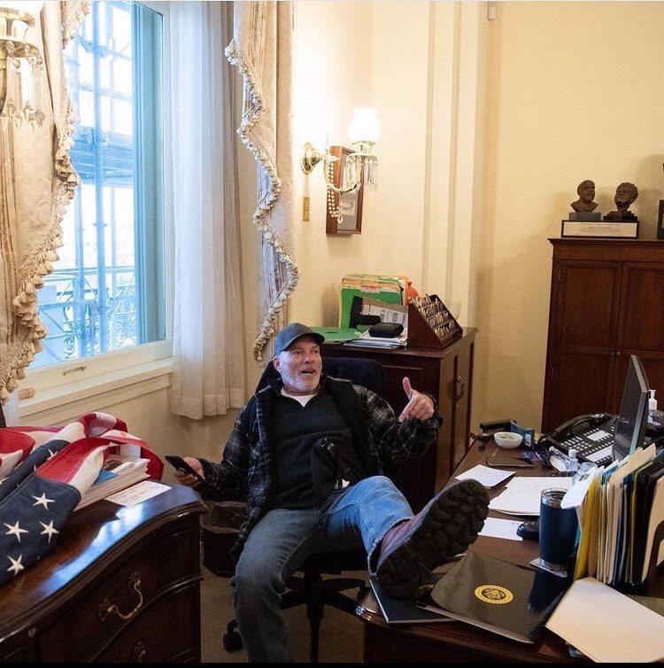 أحد المحتجين يجلس على مكتب رئيسة مجلس النواب الأمريكي نانسي بوليسي/ social media