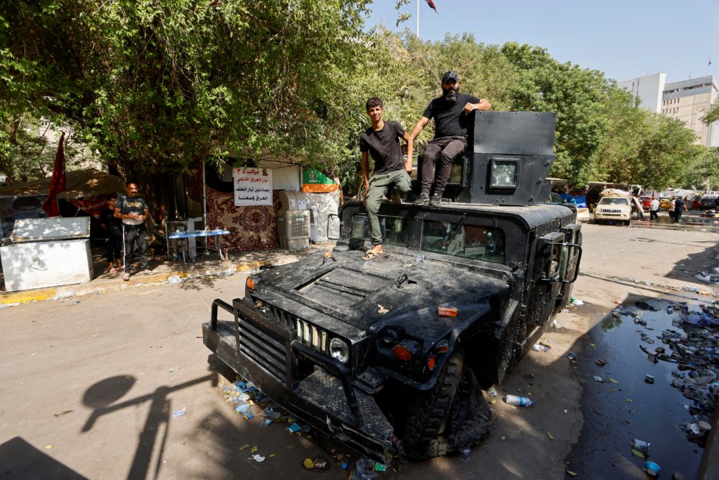 مسلحون من ميليشيات مقتدى الصدر يعتلون مركبة محترقة لقوات الأمن العراقية/ رويترز