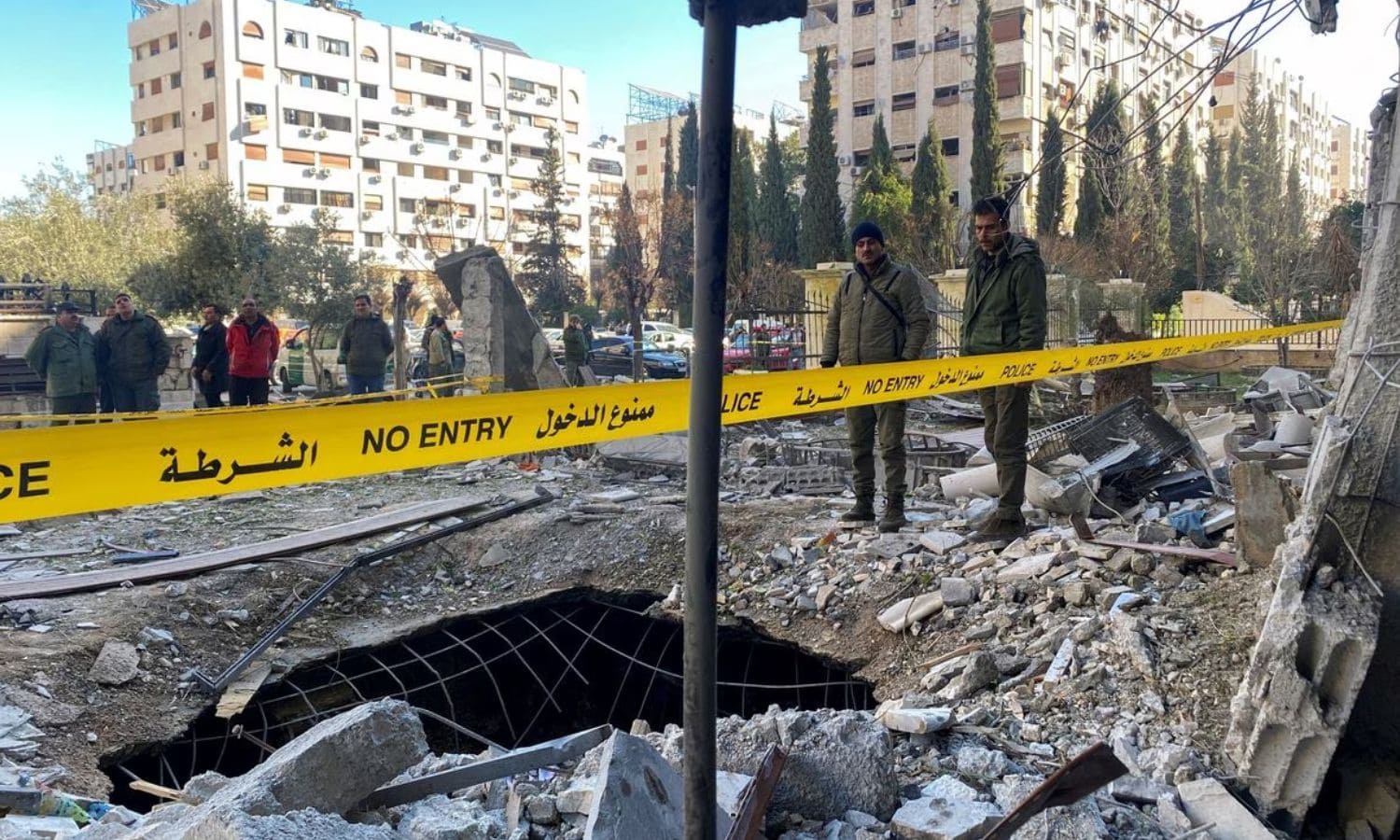 ضباط وعناصر من الشرطة والأمن يقفون وسط أنقاض مبنى مدمر في موقع هجوم صاروخي في حي كفرسوسة في دمشق/رويترز