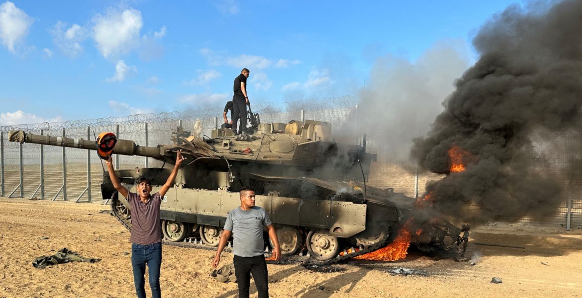 فلسطينيون يحتفلون باحتراق مركبة عسكرية إسرائيلية بعد أن هاجمها مقاومون تسللوا إلى مناطق في جنوب إسرائيل خلال عملية طوفان الأقصى/رويترز